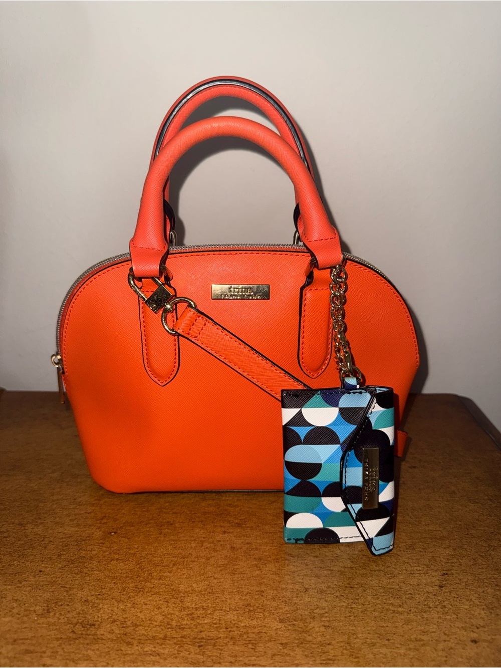 Trina Turk Dome Satchel Handbag in a vibrant, sunset orange.